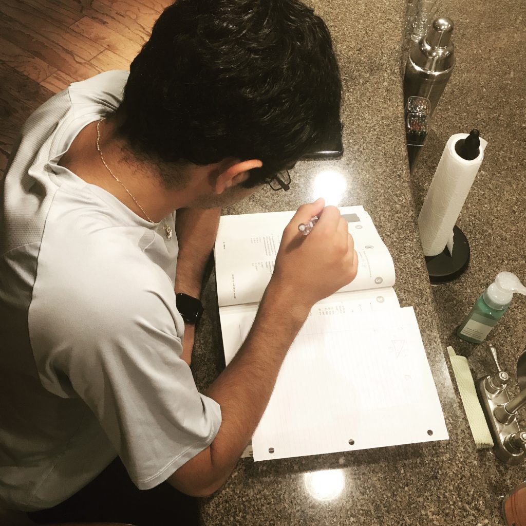 Young student sitting by kitchen counter with book open in front of him