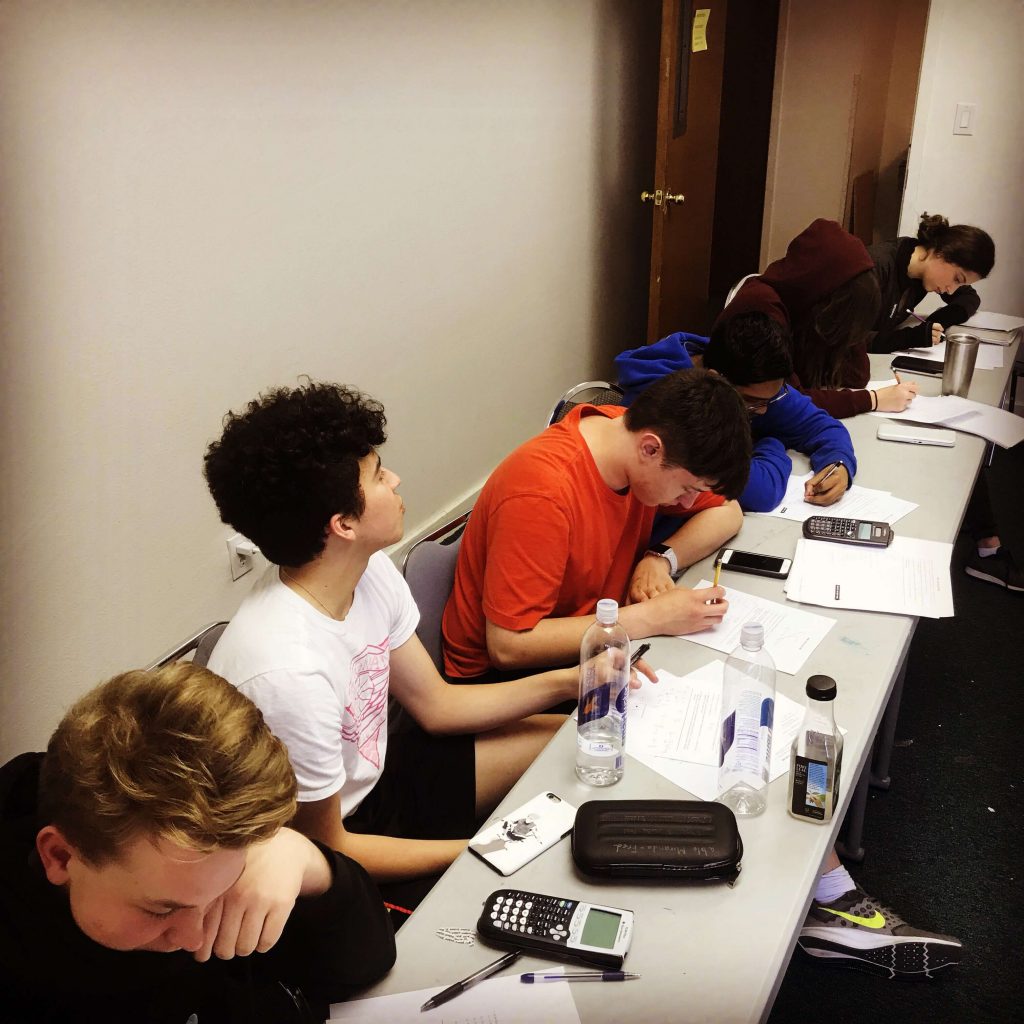 Six students sitting at a table learning math